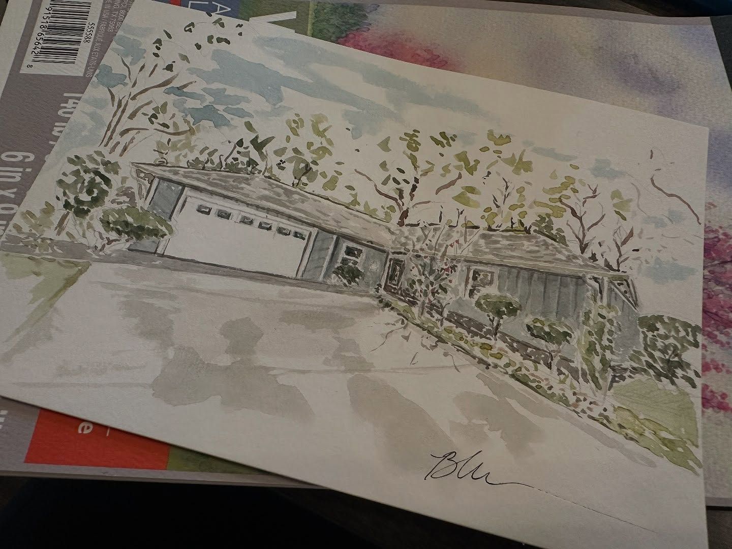 Finished watercolor portrait of a ranch-style house with a garage and soft green landscaping